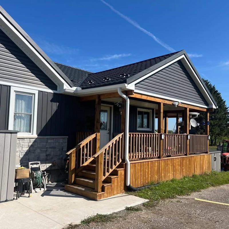 Covered front porch in stained wood on a house with dark siding and a stone base
